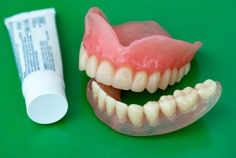 A set of dentures and a tube of denture adhesive cream.